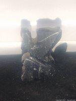 Small dark banded onyx cat sculpture viewed on a flat surface, showing the side profile with raised paw and visible stone bands.