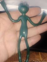 Front view of green bendable rubber frog figurine held in hand to show scale and details