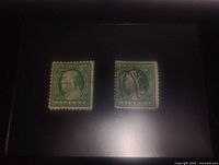 Two Benjamin Franklin one cent US postage stamps displayed side by side on a black background, showing printed details and cancellation marks.