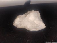 Photo of the white marble mineral specimen rock on a black background, showing its irregular shape and texture.