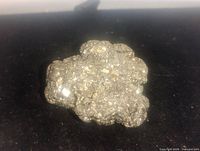 Metallic, shiny iron pyrite nugget with cubic crystal formations on a dark background.