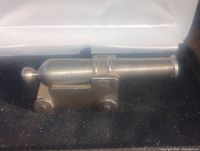 Photo of heavy metal canon decor item placed on black surface.