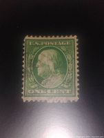 Front view of a single green Benjamin Franklin U.S. postage stamp showing clear details and perforated edges.