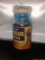 Front view of blue glass bottle showing vintage label with text 'Little Boy Blue Gunmetal Bluing' and illustration of figure.