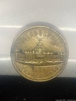 Close-up image of the front face of a round metal button embossed with the Temple of Art building and inscriptions 'PHILADELPHIA' and '1876 TEMPLE OF ART'.