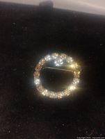 Photo showing the round rhinestone brooch resting on a black background, highlighting sparkle and shape