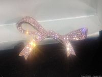Front view showing rose gold colored bow brooch fully covered with sparkling rhinestones reflecting light.