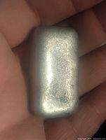 Close-up image showing size and surface texture of the pewter ingot held in hand.