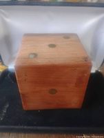 Closed cube-shaped dice box made of walnut with brass inlay dots visible on the sides and top.