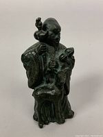 Front view showing elderly man holding staff and peach beside deer