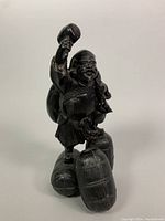 Front and left angled view of antique cast metal figurine showing detailed face, mallet held up, and barrels the figure is standing on