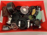 Box with assorted camera lenses, lens caps, lens cases, and lens accessories packed inside