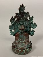 Front view of the seated Buddha figurine showing detailed facial features, robe folds, lotus base and flaming halo design.