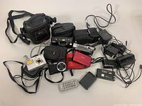 Overall lot layout showing cameras, cases, chargers, batteries and remote control