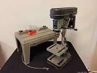 Front angled view of drill press showing cast iron base, adjustable table and column