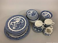 Full set overview showing all stacked plates, bowls, cups, saucers, and creamer with large serving plate at bottom