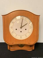 Front view of Junghans wooden wall clock showing curved top, white dial, and wood casing.