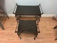 Photo showing both nesting tables stacked with smaller table underneath larger one on wood floor