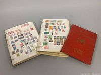 Overview photo showing three vintage stamp albums including one red hardcover and two loose-ring binders containing stamps.