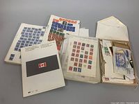 Overview of multiple stamp albums, loose stamps in an envelope and box, and a Canadian stamp booklet