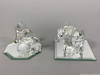 Two Swarovski crystal figures shown side-by-side on mirrored bases. Elephant figure is detailed and faceted with a chip on one ear visible. Butterfly figure shows gold-tone antennae and multi-faceted wings.
