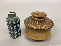 Front view of both vintage ceramic pieces showing the square vase with geometric glaze and the round vessel with ridged neck.