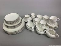Complete set of Wedgwood bone china arranged to show plates, cups, saucers, and serving pieces with silver rims in Doric pattern.
