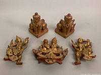 Overview of all five carved wood Asian style figurines showing seated figures, dancing figures and dual figure piece.