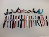 Photo showing a variety of wristwatches arranged in two rows, featuring various colors and strap materials.