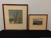 Two framed antique etchings displayed side by side on a wall. The larger etching shows a church, the smaller a landscape scene.