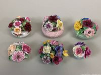 Six pieces of vintage bone china floral bouquet figurines arranged on flat surface showing different colors and flower types.