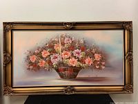 Full view of framed oil painting depicting a basket of flowers with gold ornate frame.