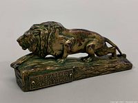 Side view of bronze lion paperweight showing detailed sculpture and plaque on the base.