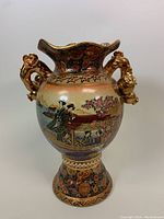 Front side of the Satsuma vase showing geisha figures and floral motifs with gold floral handles.