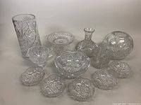 Assorted vintage cut crystal pieces including vase, decanter, compote bowl, small trays and dishes arranged on white background