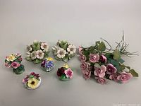 Group shot showing 4 floral bouquets, 10 pink artificial roses, and 2 porcelain candleholders