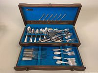 Full view of wooden chest open showing organized flatware inside.