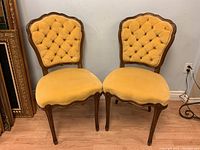 Pair of Victorian style side chairs with yellow velour upholstery and dark carved wooden frames.
