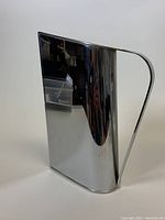 Side view showing the mirrored finish, angular handle, and the overall geometric design of the pitcher.