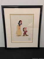 Framed Snow White and Grumpy artwork showing entire framed piece on wall.