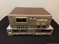 Front view of stacked Realistic SCT-20 cassette deck on top of Technics M235X cassette deck showing entire units, controls, and woodgrain sides on Realistic deck.