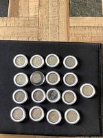 Seventeen Canadian silver quarters arranged in three rows in protective plastic holders, showing obverse side profile images of monarchs.