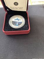 Photo showing the 2008 $30 sterling silver coin with colorized shark design inside red presentation box with certificate of authenticity from Royal Canadian Mint.