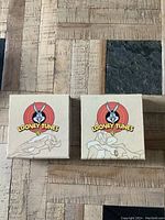 Two unopened Looney Tunes coin boxes showing packaging featuring Bugs Bunny and Wile E. Coyote with Looney Tunes logo.