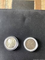Two 1966 Canadian silver dollar coins front side with Queen Elizabeth II portrait in protective capsules on black surface.