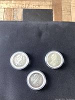 Front side showing Queen Elizabeth II portrait on the three 1967 Canada silver dollar coins in protective cases.