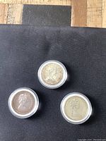 Obverse side of three Canadian silver dollar coins in protective capsules showing Queen Elizabeth II