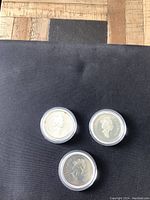 Three Canadian silver dollar coins showing obverse with Queen Elizabeth II profiles in capsules.
