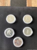 Top side of five Canadian silver dollar coins showing various commemorative designs from 1975, 1977, and 1983, housed in individual protective cases.