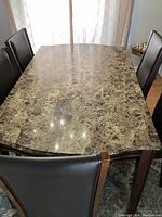 Top view of rectangular dining table with marble-patterned surface and six chairs around it.